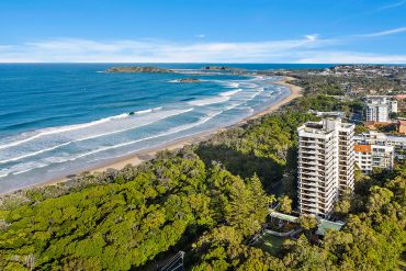 Pacific Towers Beach Resort building overlooking the ocean with lush surroundings